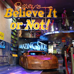 Entrance to Ripley's Believe It or Not! museum featuring a wooden car sculpture and neon signage. People are visible inside.
