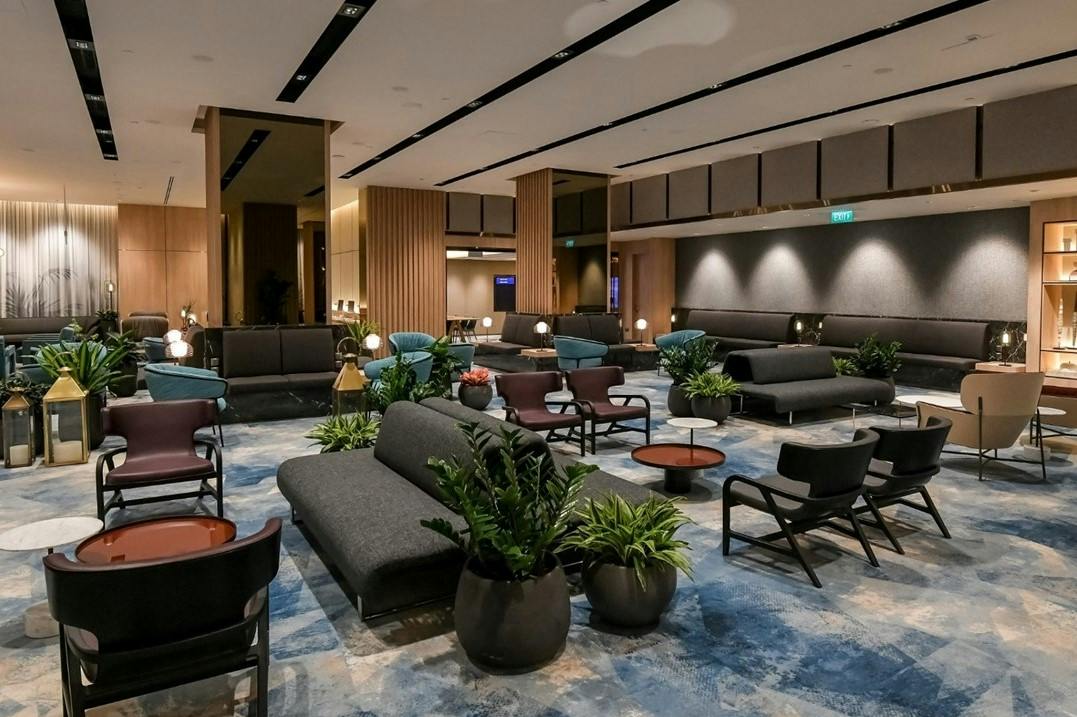 Een moderne zithoek met banken, fauteuils, salontafels en potplanten, met sfeervolle verlichting en een eigentijds ontwerp.