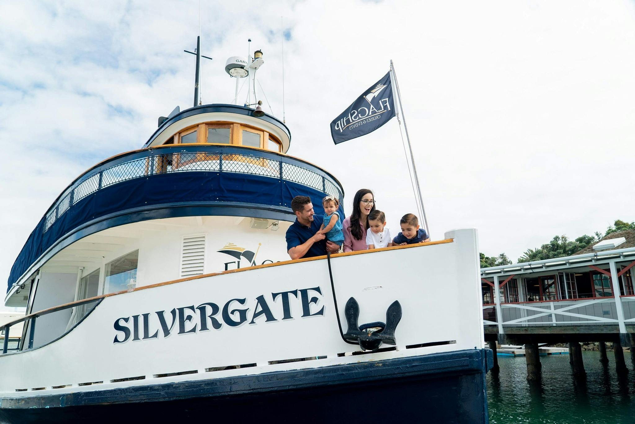 一家五口站在一艘名为「Silvergate」的游艇上，微笑着眺望水面。