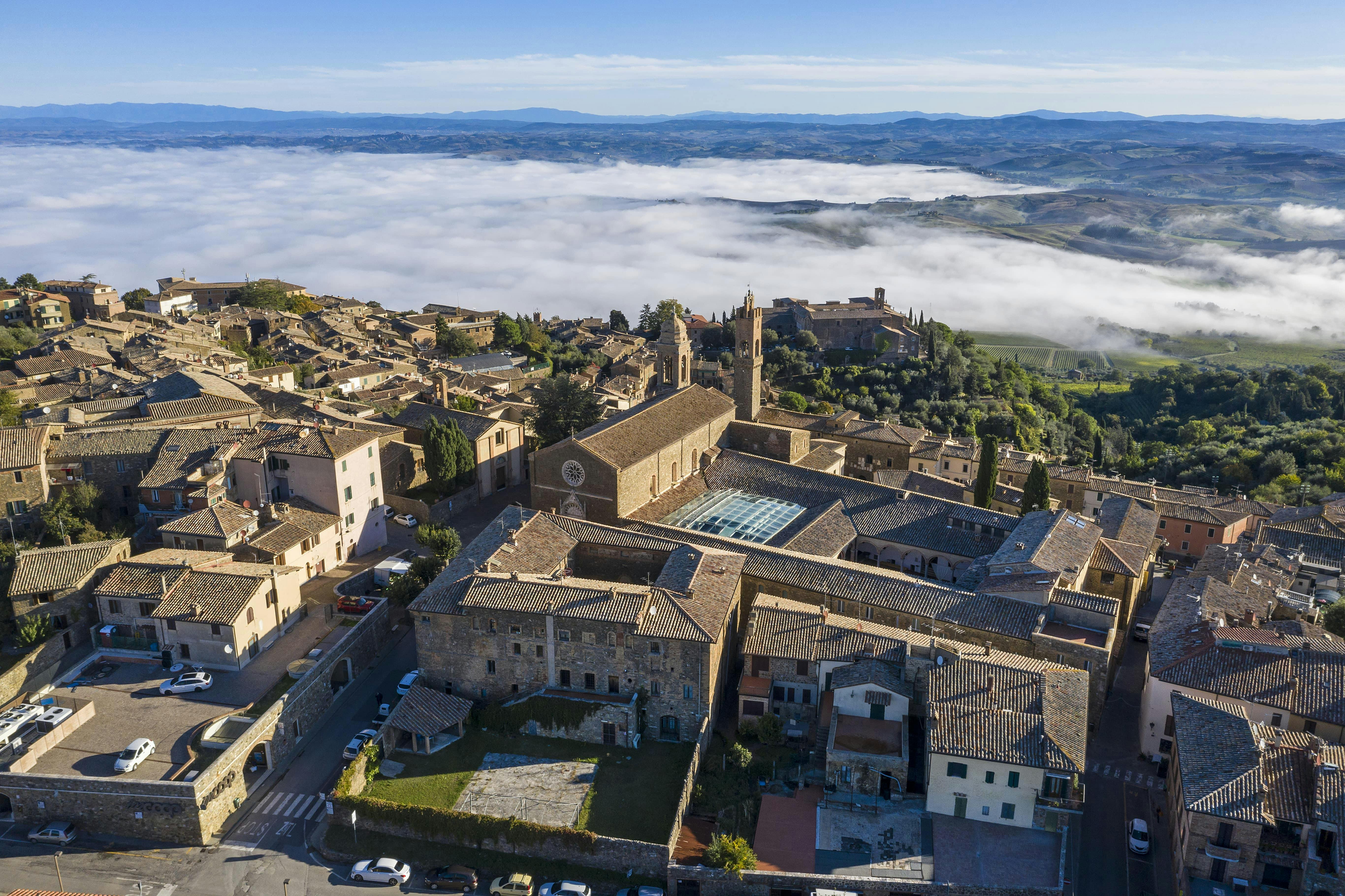 意大利蒙塔尔奇诺（ Montalcino ）的鸟瞰图，设有历史建筑、中央庭院和低洼雾霾环绕的乡村。