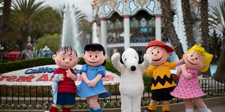 Five costumed characters posing happily in front of a carousel and fountain at California's Great America amusement park.