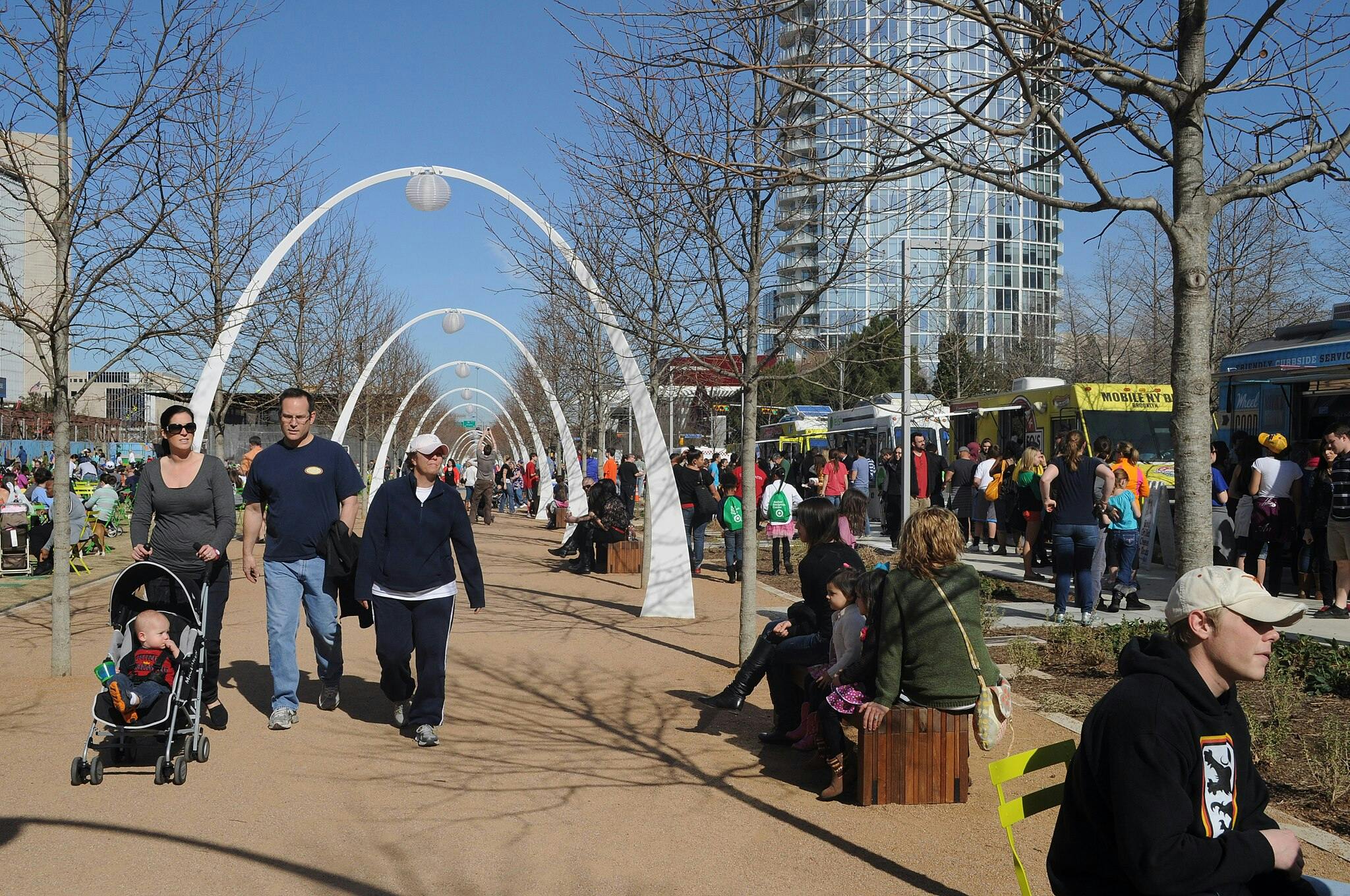 小径两旁是无叶树木和满是人的白色拱门。 街头小贩和快餐车就在右手边。