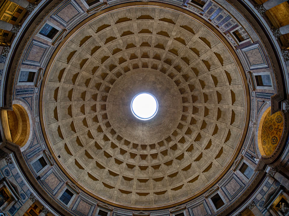 Interior view of a large dome with a central circular opening and a coffered ceiling pattern, with architectural details visible.
