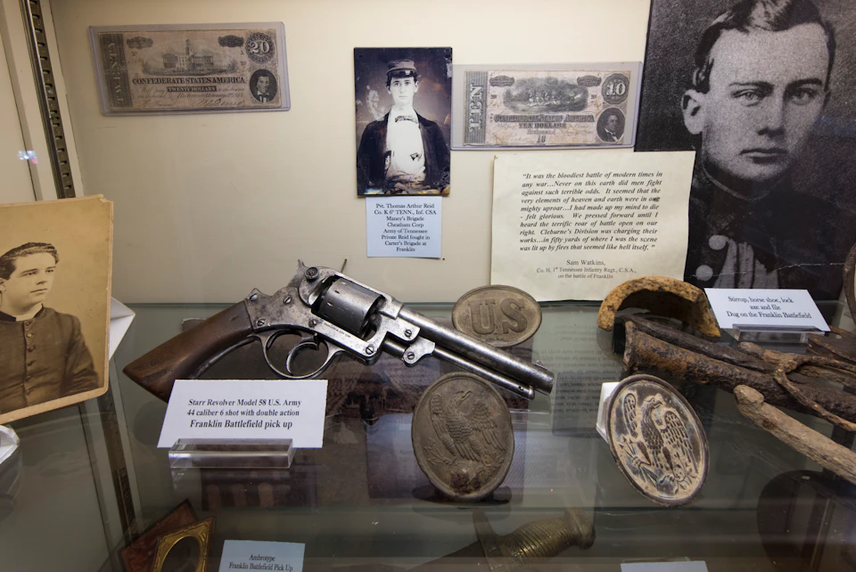Display case containing a Starr Revolver Model 3, historical photos, currency, and military memorabilia with informational labels.