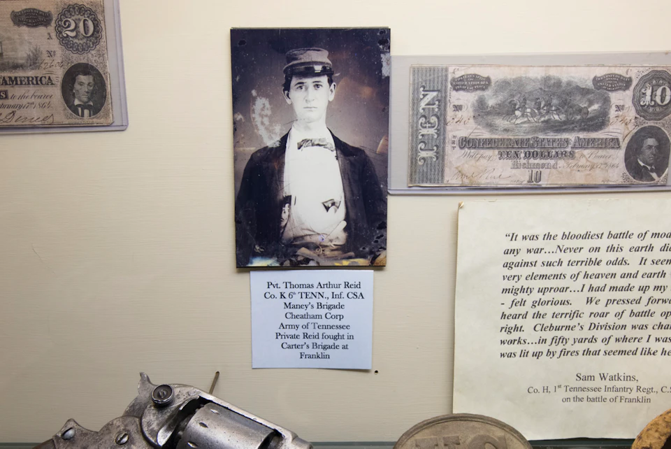 Display case containing a Starr Revolver Model 3, historical photos, currency, and military memorabilia with informational labels.