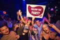 Un gruppo di partecipanti al pub crawl in posa per un selfie di gruppo con il cartello "Follow the Party - pubcrawl.pl".