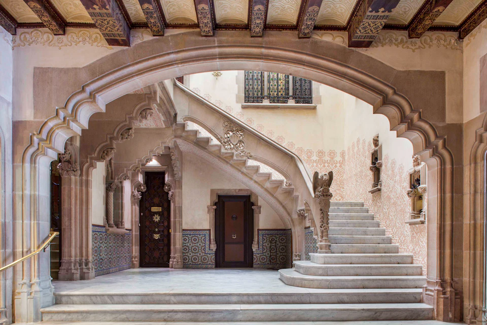 Intricately designed interior features ornate stone archways, a staircase with detailed balustrades, and decorative tiles on the walls.