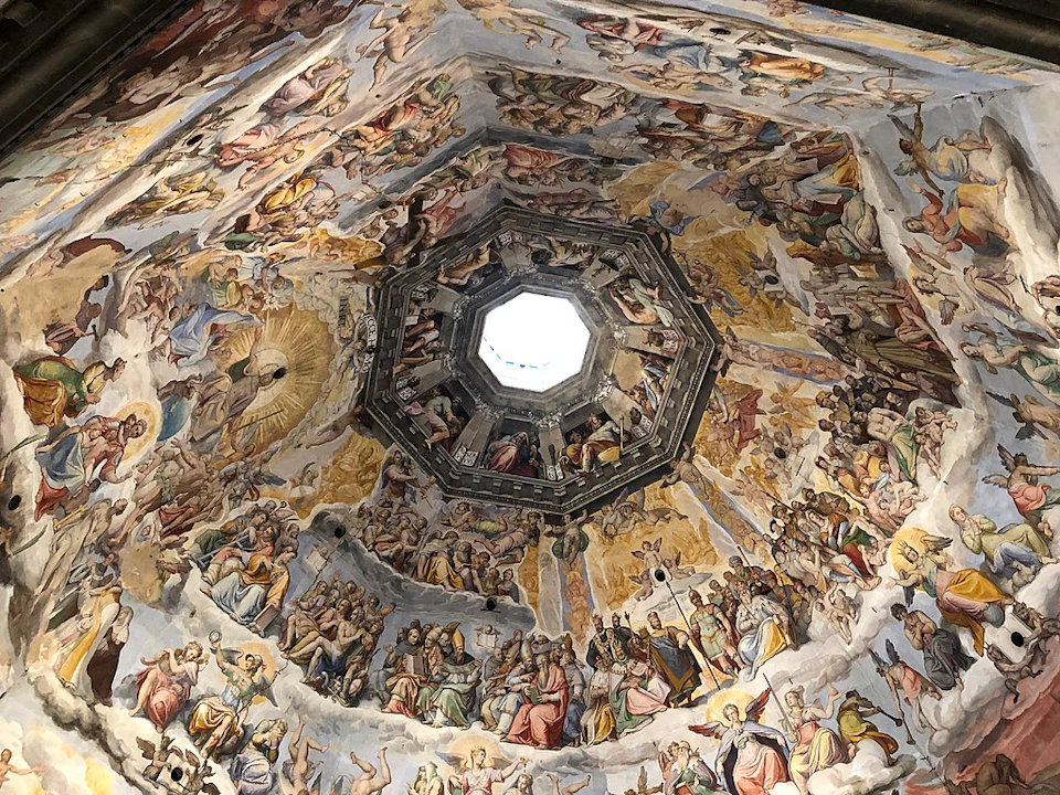 Intricately painted interior of a dome depicting religious figures and scenes, with a central skylight.