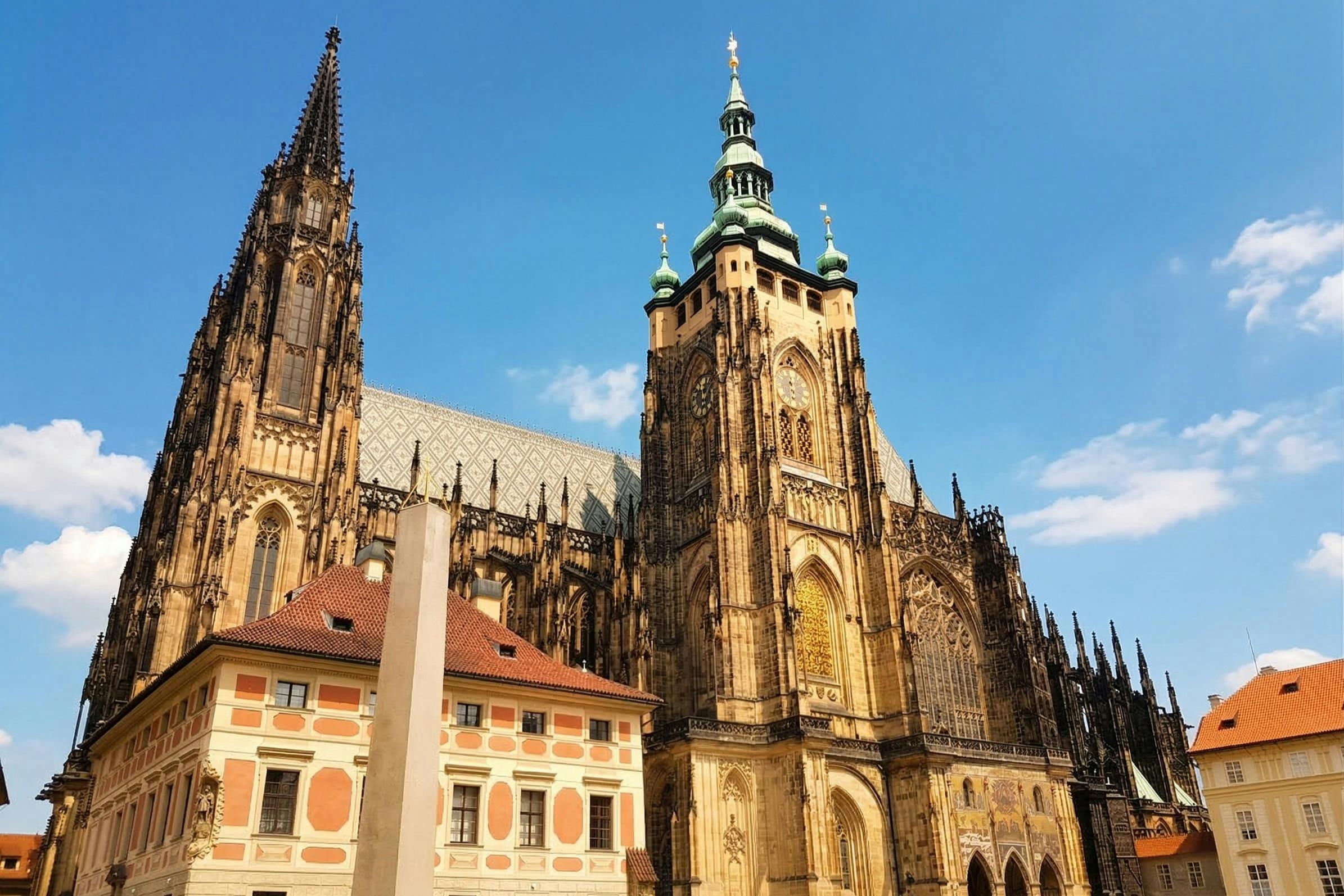 Een gotische kathedraal met uitgebreide spitsen en torens, naast kleurrijke gebouwen onder een strakblauwe hemel.