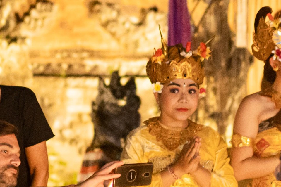 People in traditional costumes and casual attire perform a ceremonial activity with fire in a cultural setting at night.