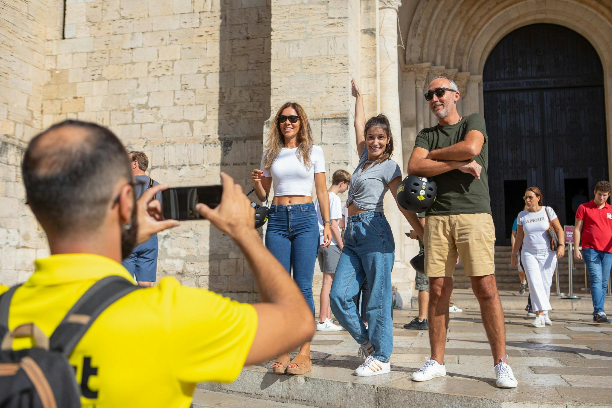 Touristes profitant d'une visite en E-Bike à Lisbonne avec un arrêt photo à la cathédrale de Lisbonne.