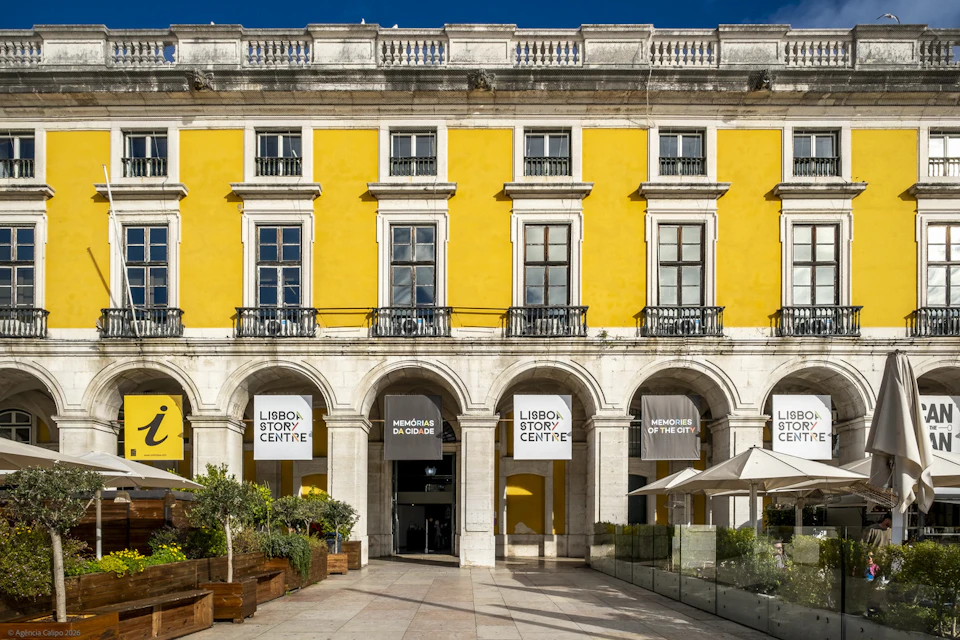 A yellow building with arched entrances and signs for "Lisbon Story Centre" and "Memories of the City."