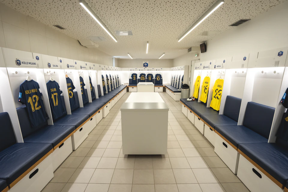 A sports team locker room with blue and yellow jerseys hanging on lockers, and a central white table.