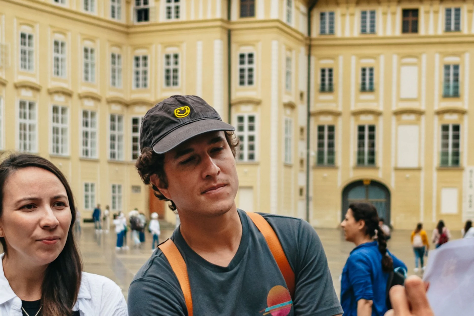 A group of people stands in a courtyard surrounded by historic buildings, one person appears to be leading or explaining something.