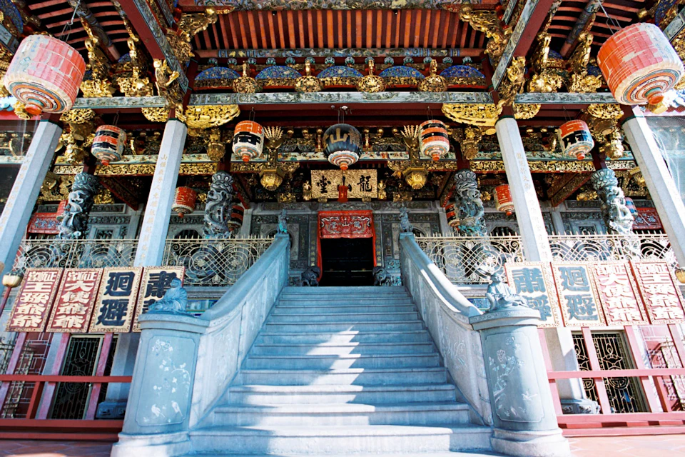 A richly decorated temple facade with ornate carvings, colorful decorations, and a staircase leading up to the entrance.