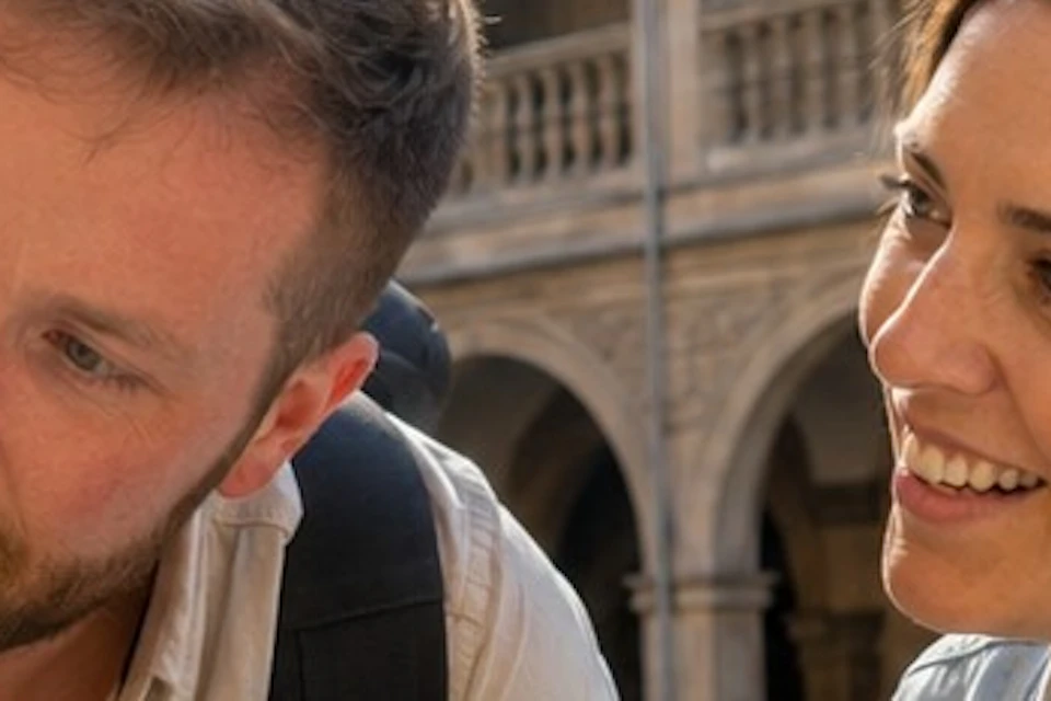 Two people observing a sculpture in a historical building courtyard with multiple arched balconies.