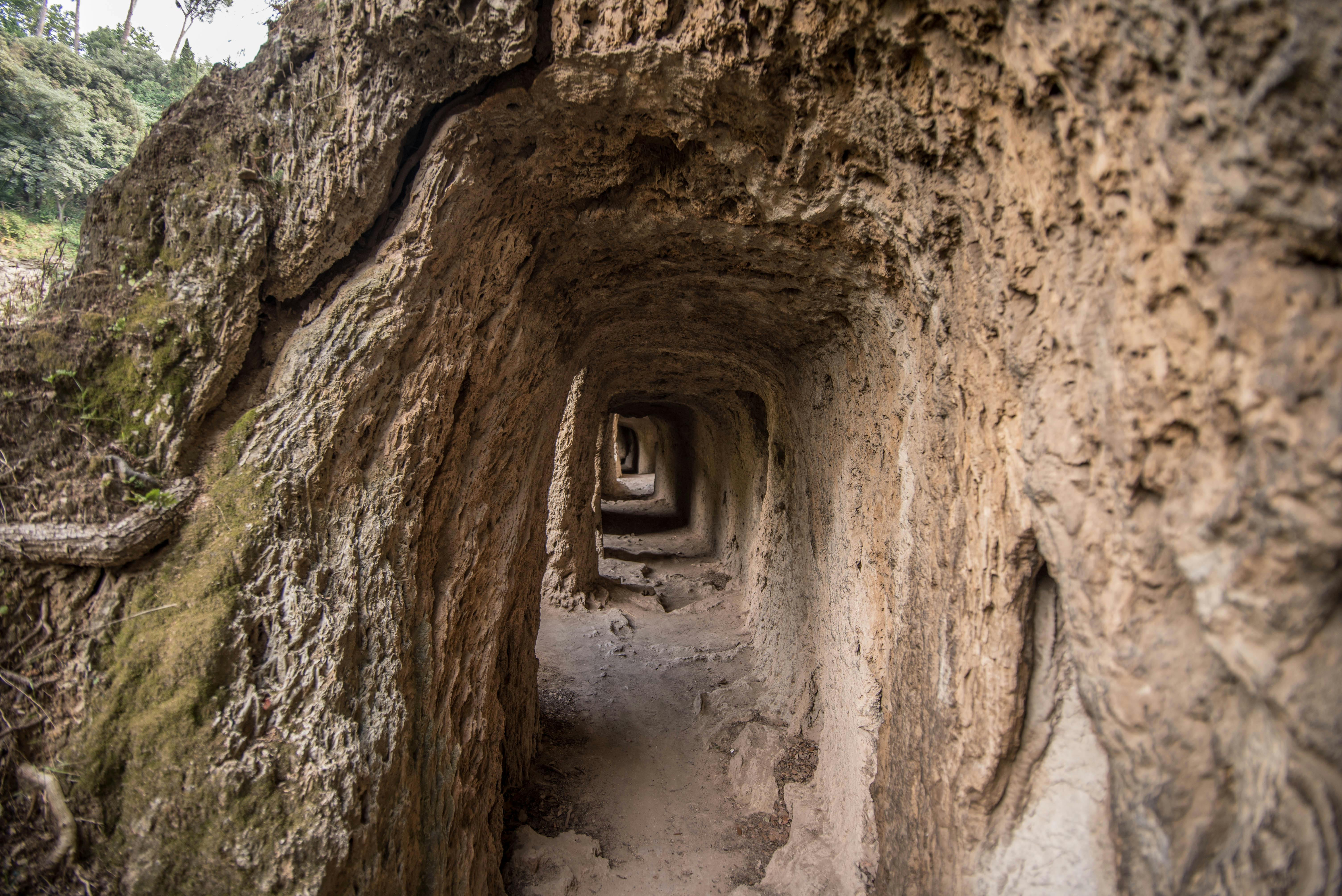 Узкий туннель с шероховатыми, скалистыми стенами, простирающимися глубоко вдаль, создавая многослойный визуальный эффект.
