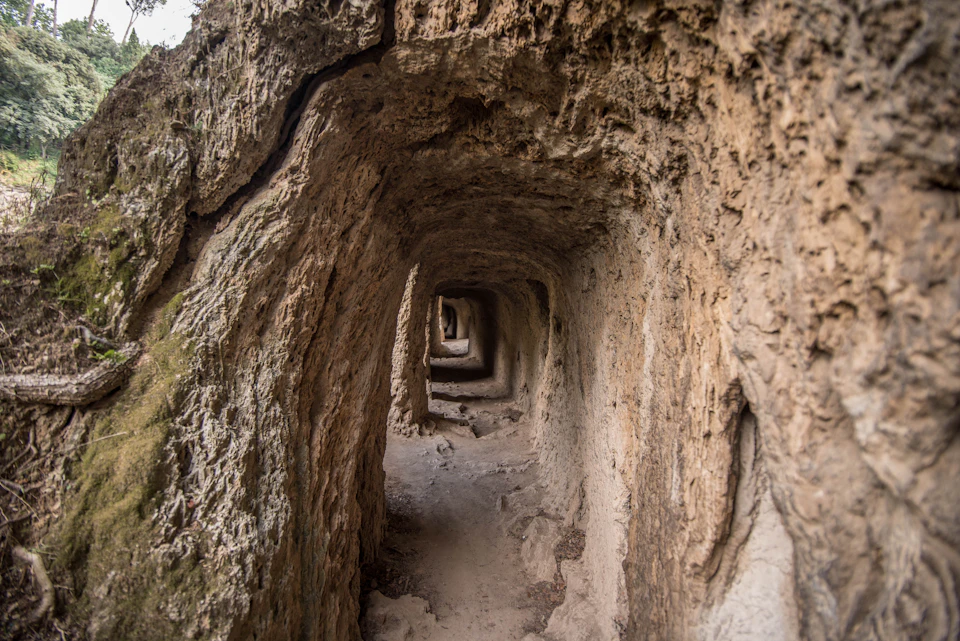 A narrow tunnel with rough, rocky walls extending deep into the distance, creating a layered visual effect.