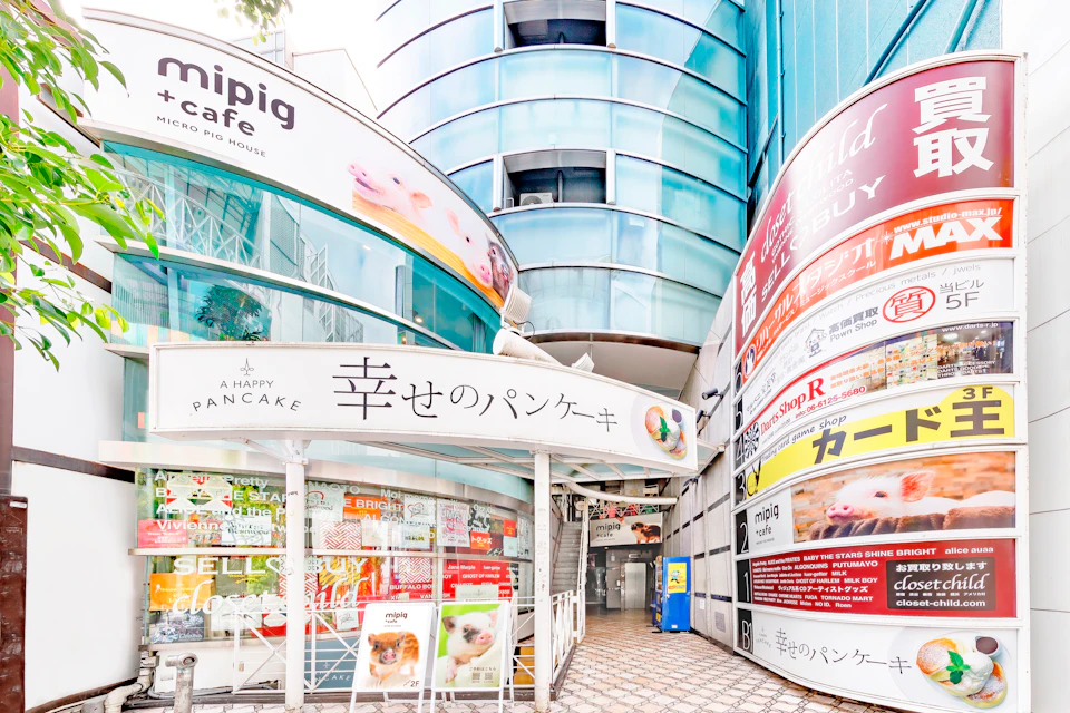 Entrance to a building with signs in Japanese and English, including "A Happy Pancake" and "mipig cafe."
