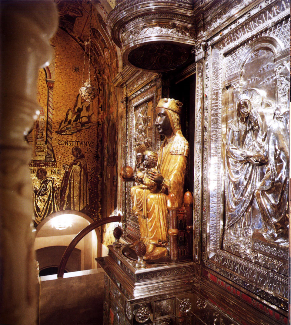 A gilded statue of Madonna and Child sits in an ornate silver and gold alcove with intricate religious carvings and mosaics.