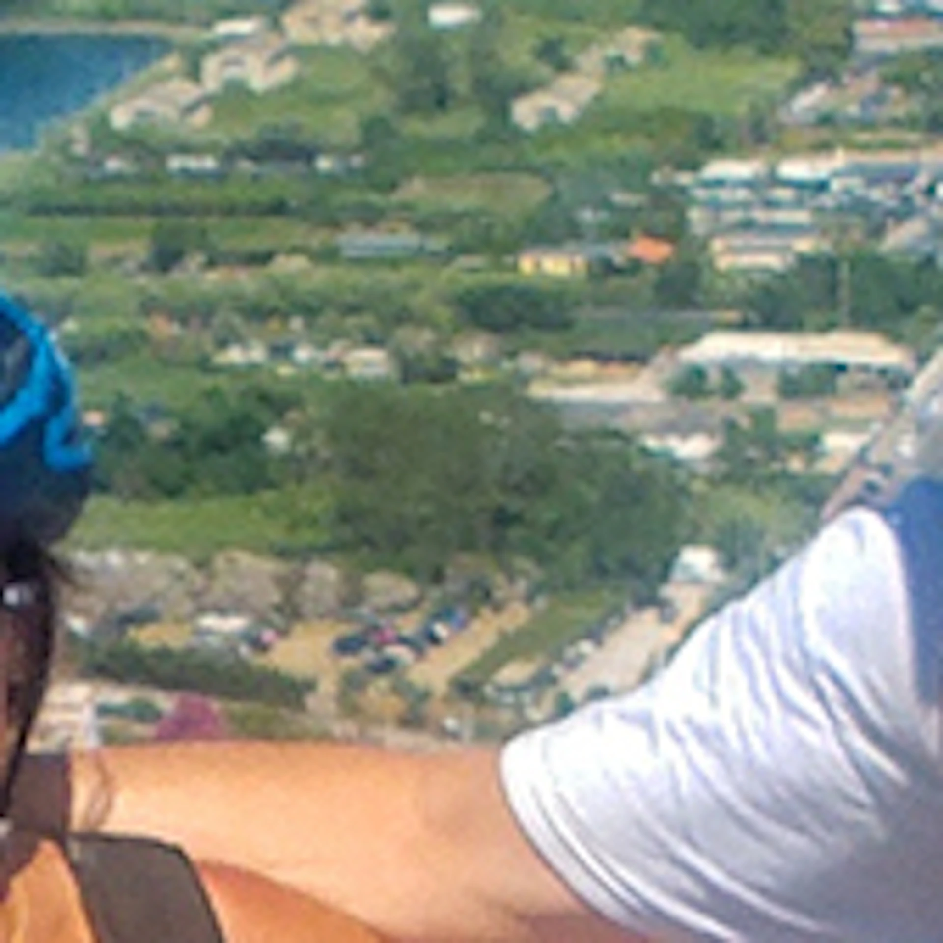 Four people wearing helmets stand with bicycles on a scenic overlook with coastal views and distant islands in the background.