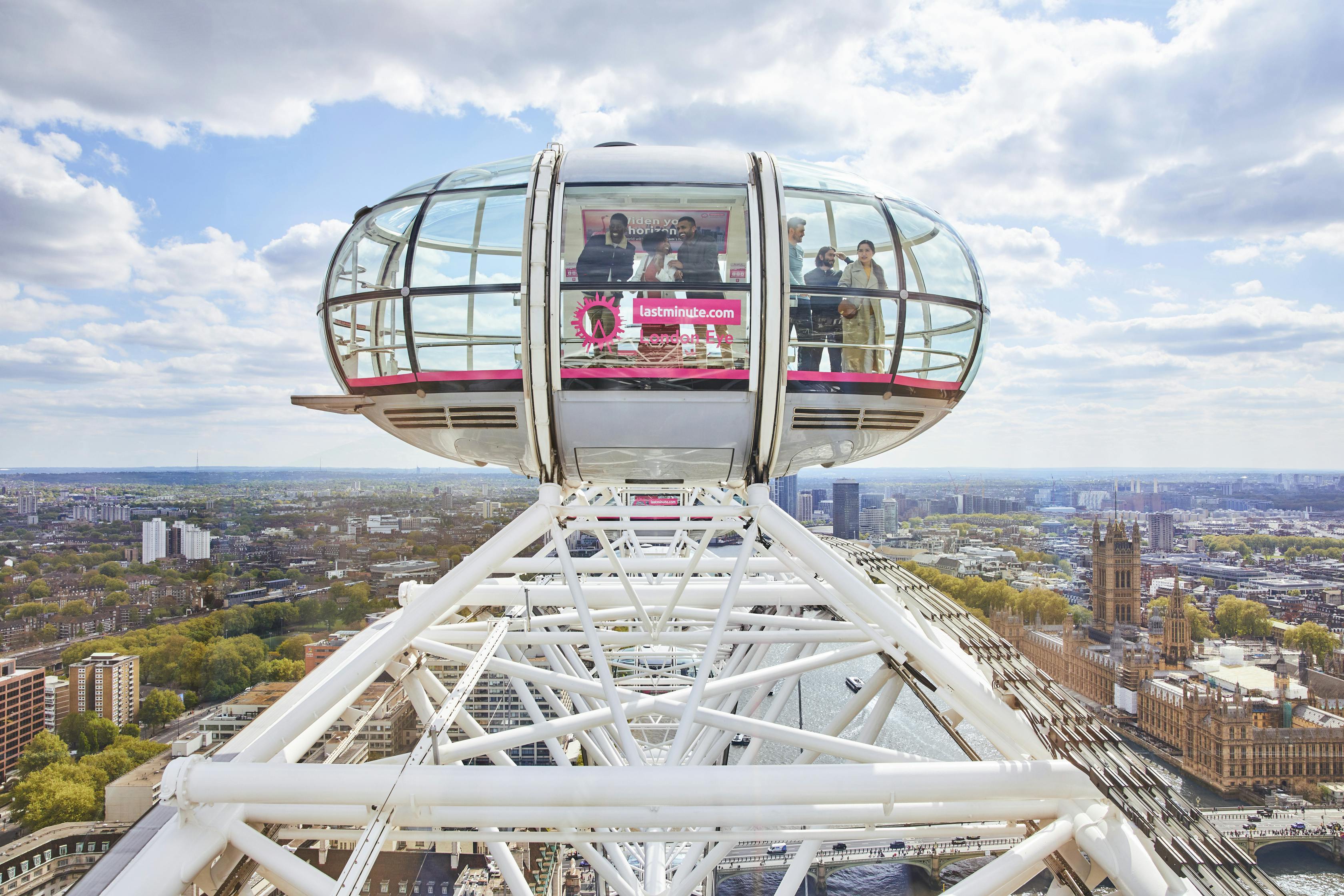 런던 아이 (London Eye) 에 있는 유리 전망대에서 여러 명이 안으로 들어가 아래 도시 풍경을 내려다보고 있습니다.