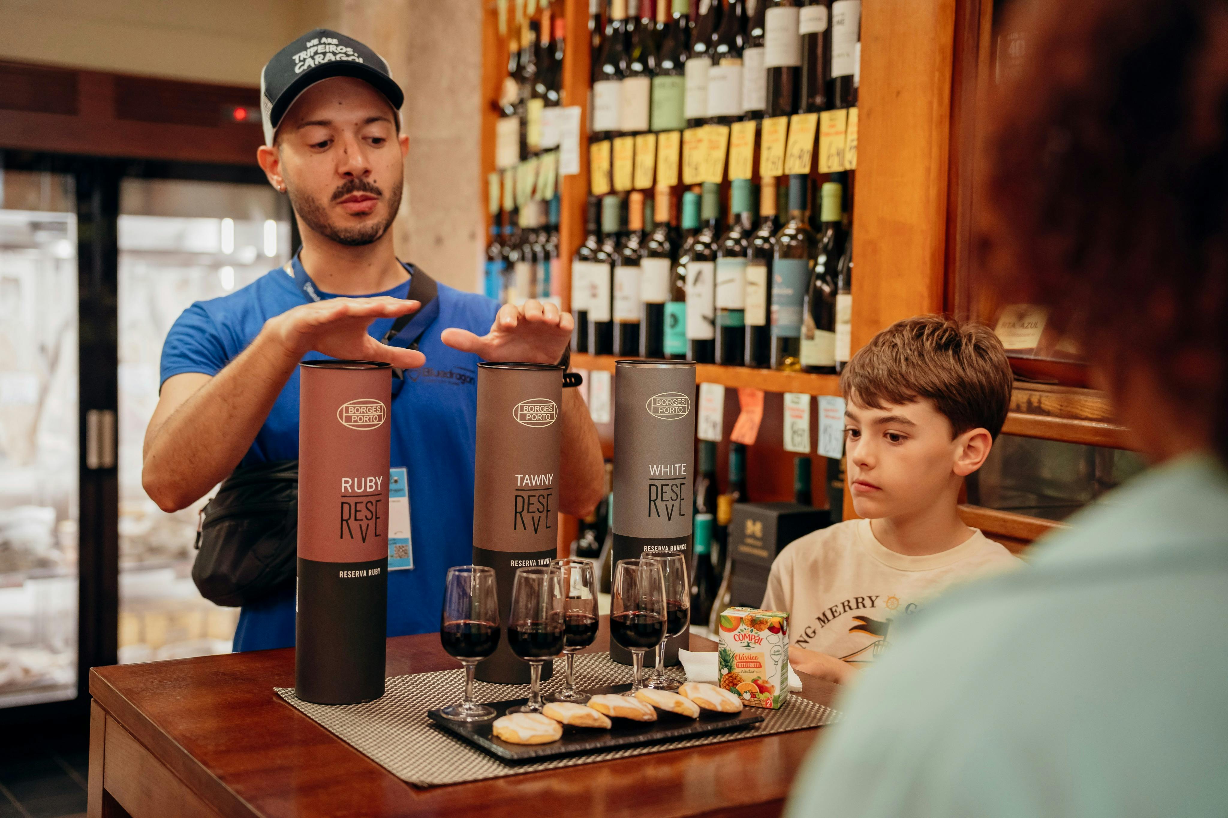 Ein Mann und ein Junge an einem Weinverkostungsstand mit ausgestellten Weinflaschen, drei Weinsorten, Gläsern und Snacks.