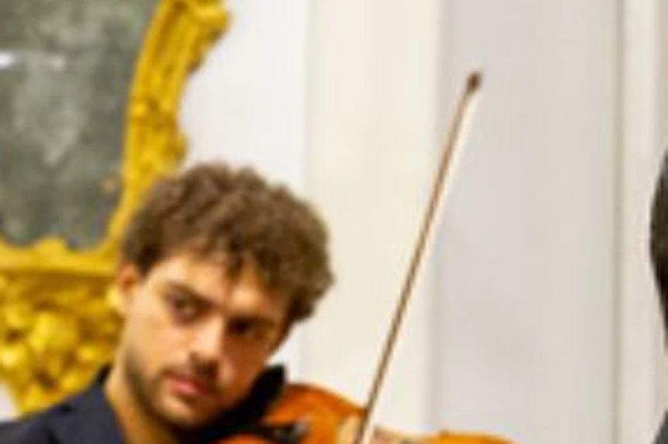 Three men in suits passionately sing while musicians play violins and cellos in the background. Text reads "THE THREE TENORS."