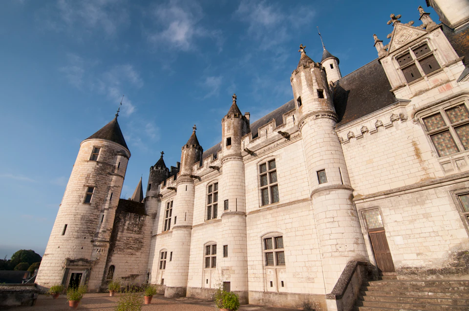 A historic white stone castle with multiple towers and turrets under a blue sky.