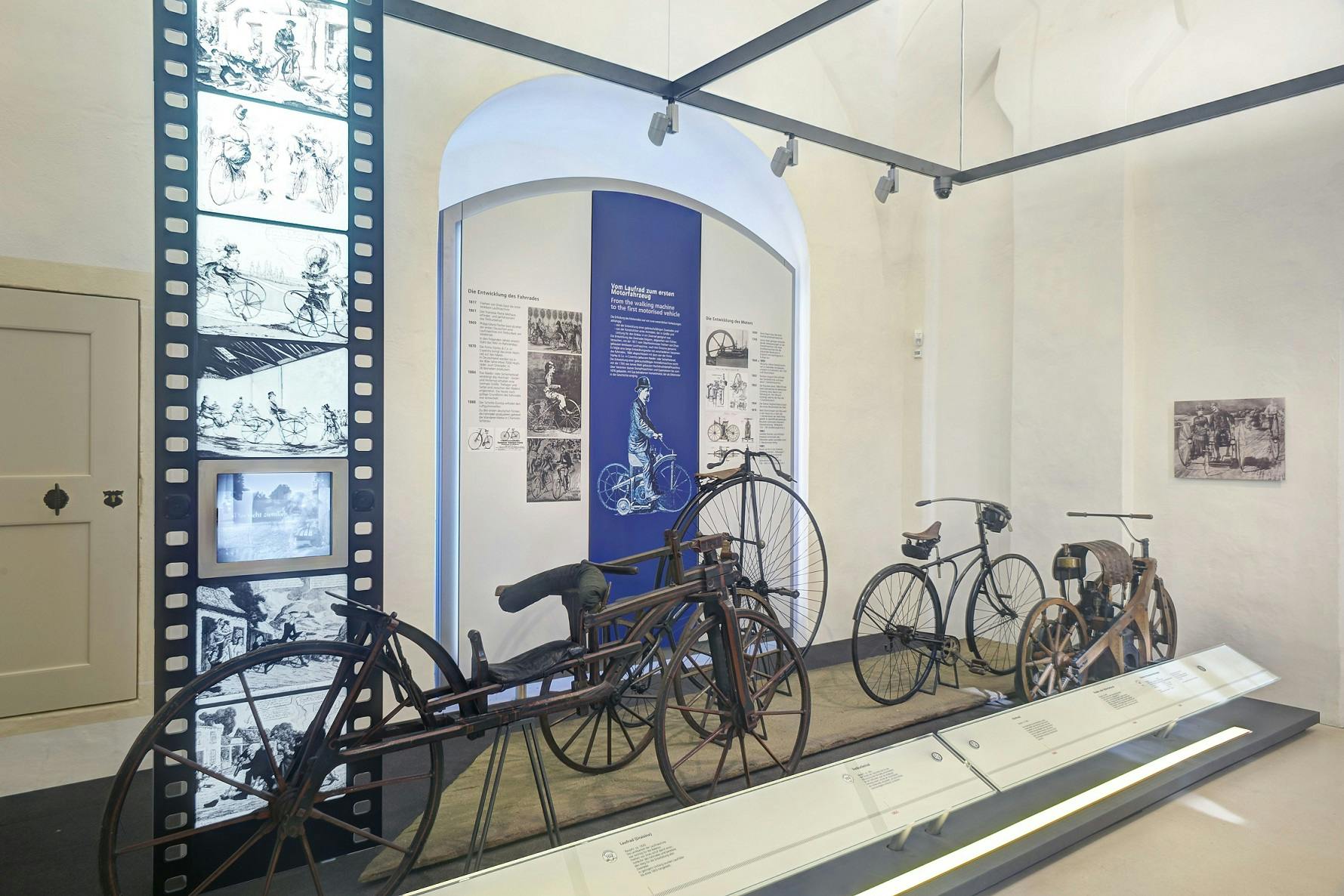 一个博物馆展览展示了老式自行车，背景有信息展示，左侧有插图。