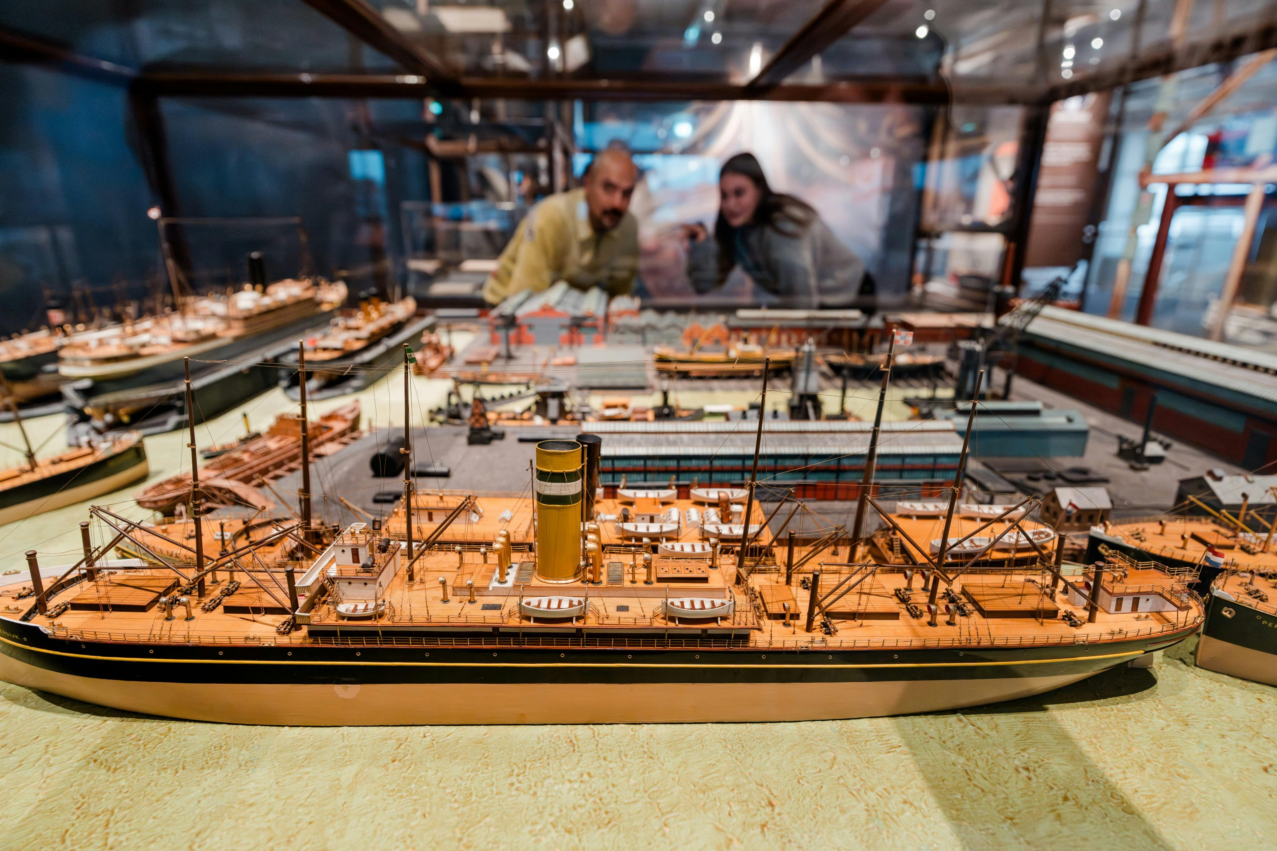 博物馆展示了一个详细的船舶模型，后面有两个人观察它。