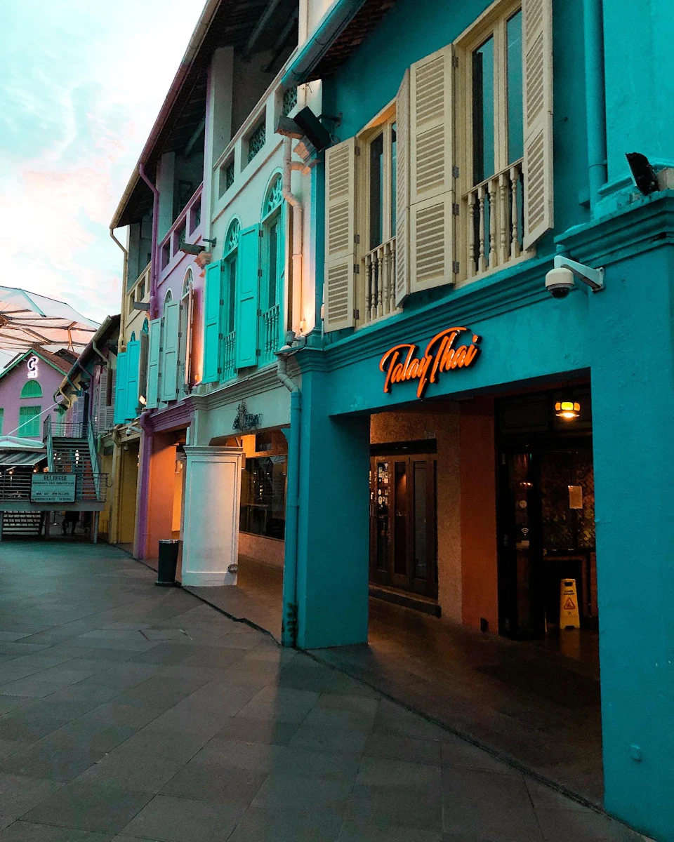 Colorful buildings with shutters line a pedestrian street. A visible sign reads "Talay Thai."