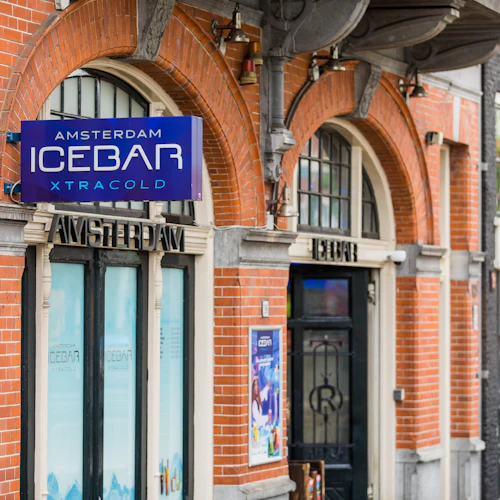 Fasad i tegel med välvda fönster och en blå skylt med texten "Amsterdam Ice Bar Xtracold".