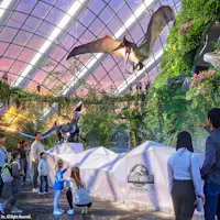 In einer futuristischen Ausstellung mit gläsernen Decken, üppigen Pflanzen und dem "Jurassic World"-Logo können die Besucher animierte Dinosaurier beobachten.