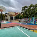 Детская площадка с баскетбольным обручем с произведениями стрит-арта на стенах и на земле.