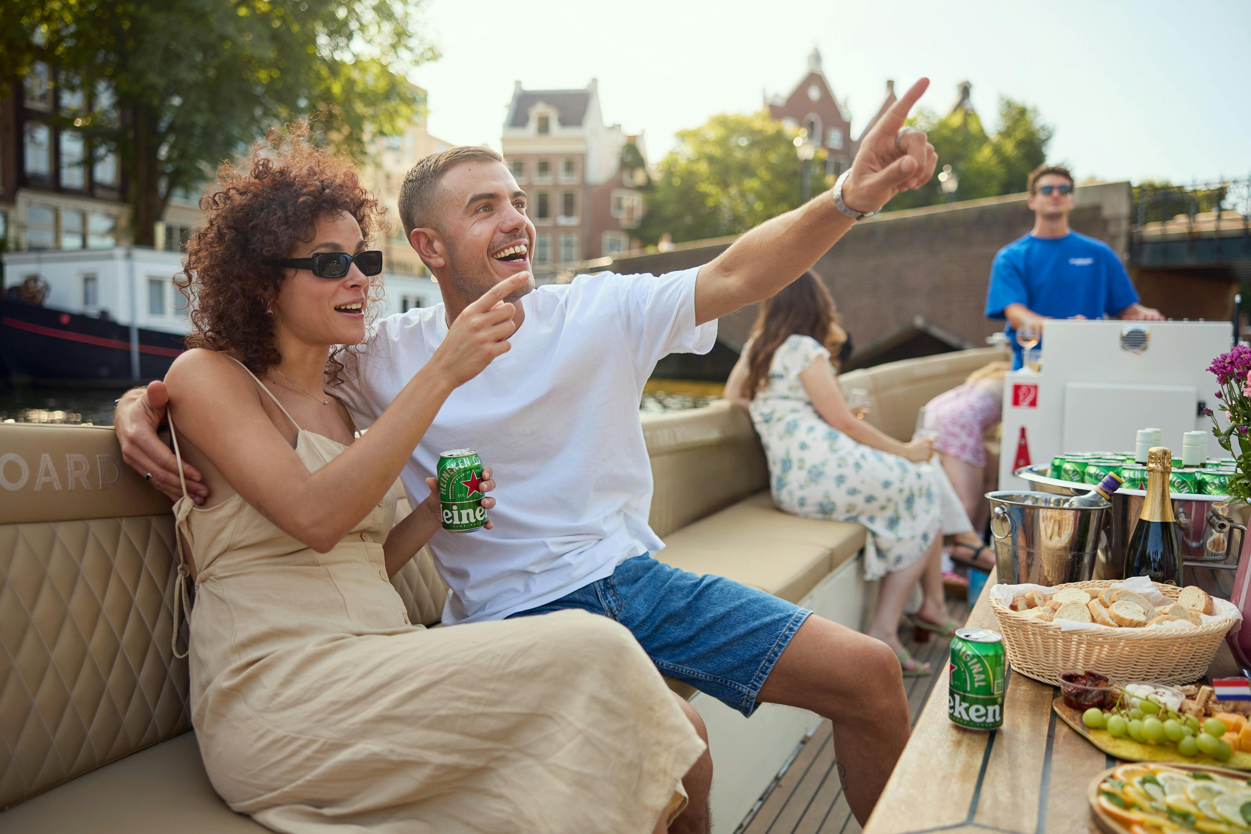 男性と女性が一緒にボートに座り、微笑んで指さしています。 背景には、晴れた日の建物や木々が写っています。