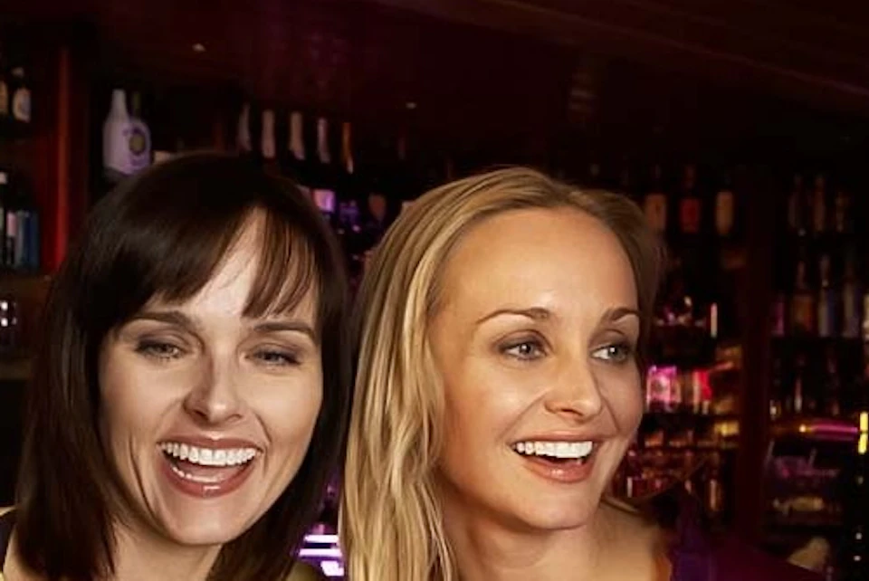 A group of smiling people drinking alcohol in a bar