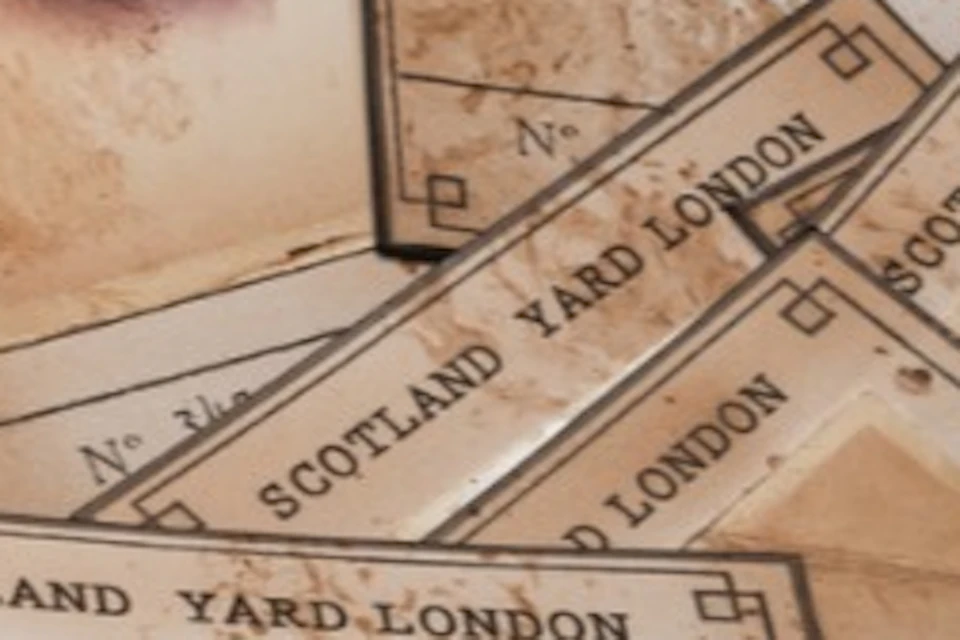 A collection of old sepia-toned portrait cards labeled "Scotland Yard London" spread out on a cloth surface.