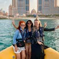 três senhoras andando nos barcos amarelos e tirando fotos em frente a um hotel 5 estrelas em Abu Dhabi