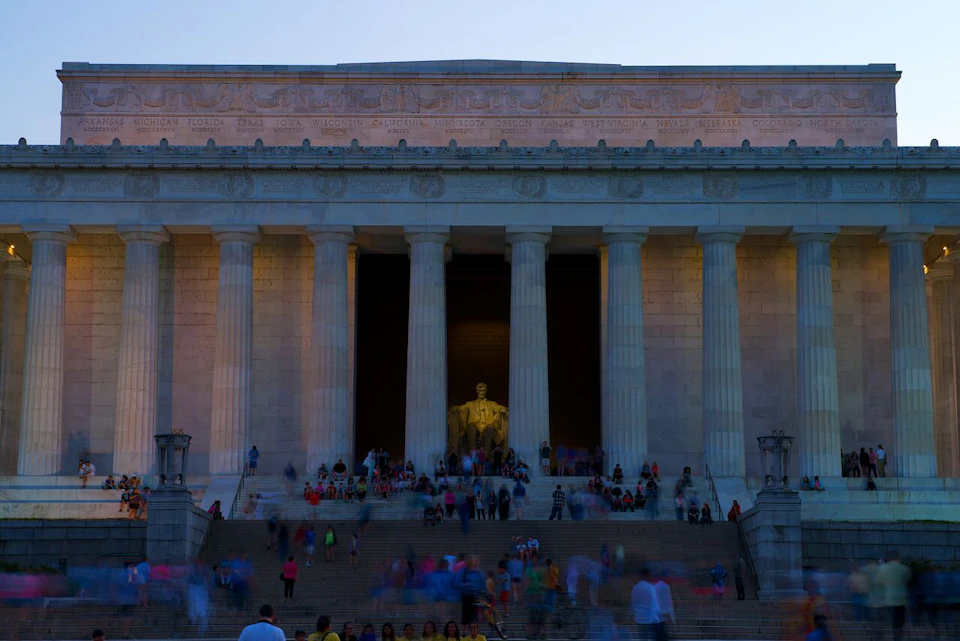 Crowd gathered at the steps of the Lincoln Memorial, centered on the seated statue of Abraham Lincoln illuminated inside.