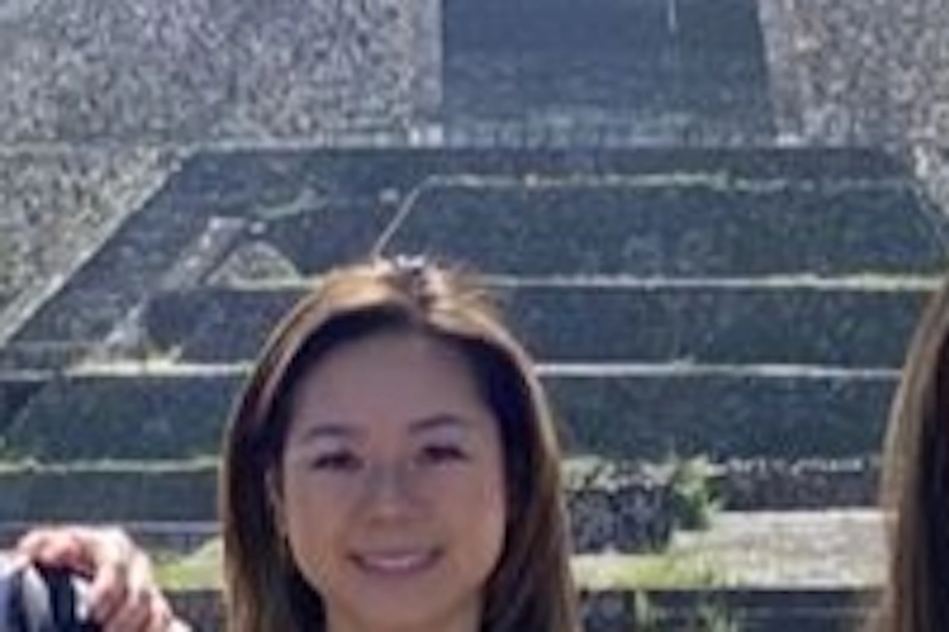 Five people posing in front of a large pyramid on a sunny day. Everyone is smiling and wearing casual summer clothes.