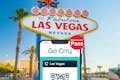 智能手机上显示拉斯维加斯Go City全包通票，背景为拉斯维加斯欢迎广告牌