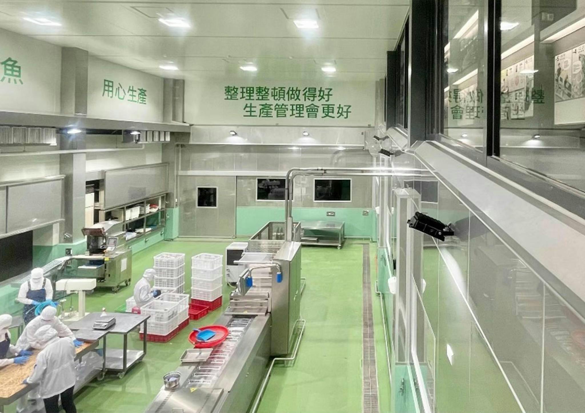A clean and organized production facility with green and white walls, machinery, and workstations, viewed from above.