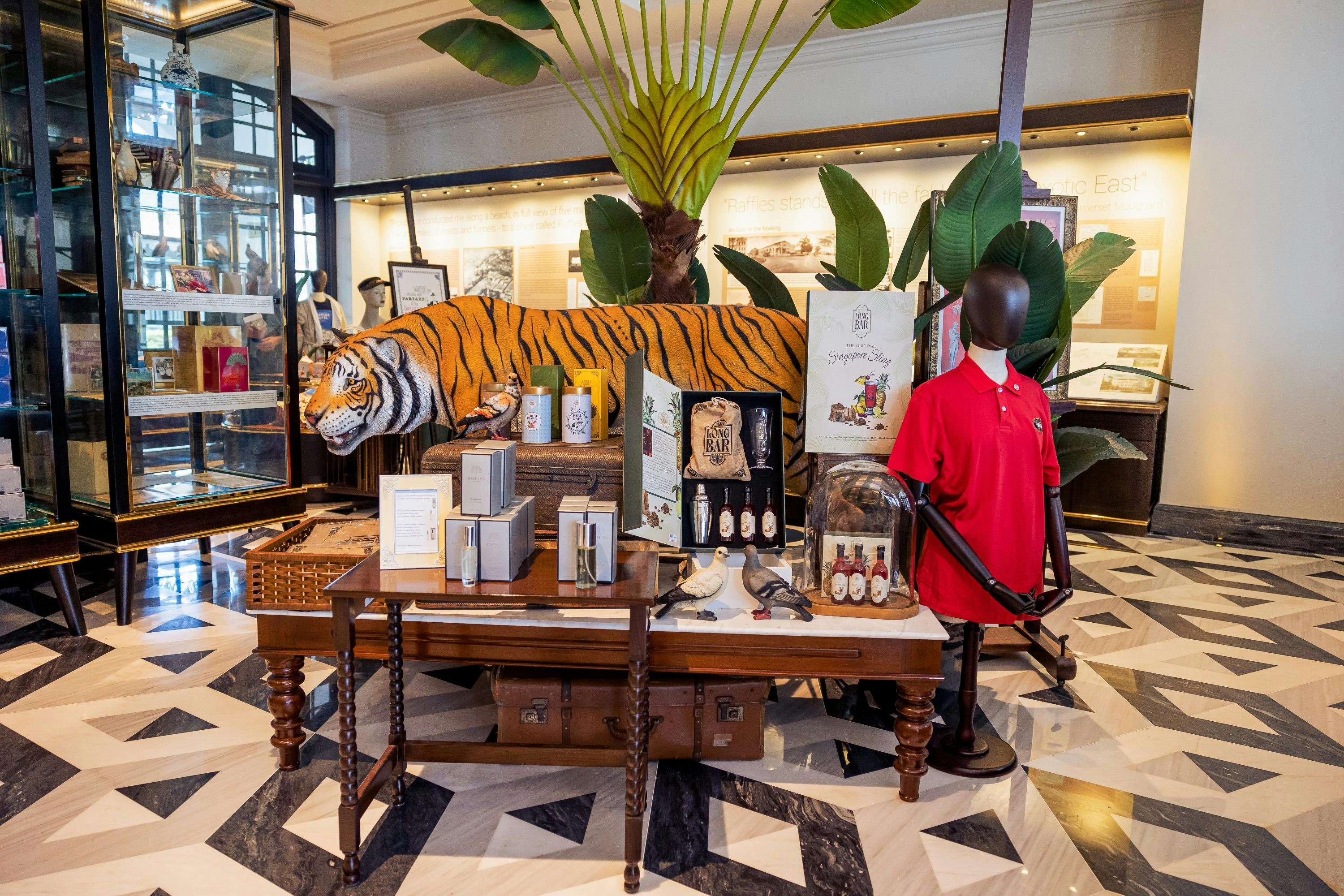 A display with a tiger sculpture, merchandise, and décor items in a store with tropical-themed interior design.