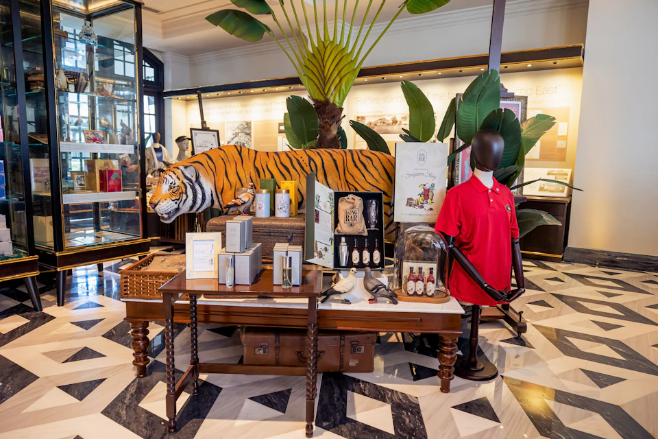 A display with a tiger sculpture, merchandise, and décor items in a store with tropical-themed interior design.