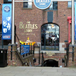 Entré till utställningen "The Beatles Story" på Albert Dock, Liverpool. Tegelbyggnad med banderoller med bandet.