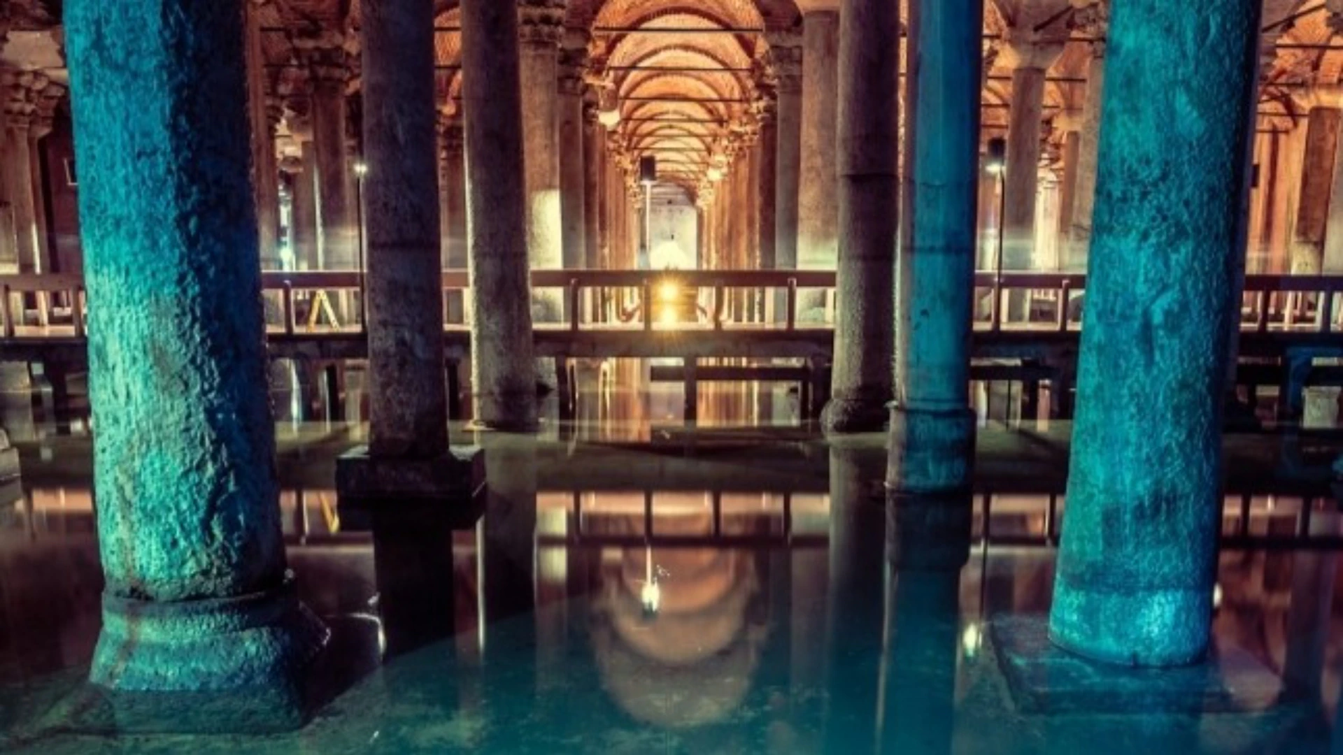 A large underground space with columns and arches reflected in the water, lit by warm lighting, creating a serene atmosphere.