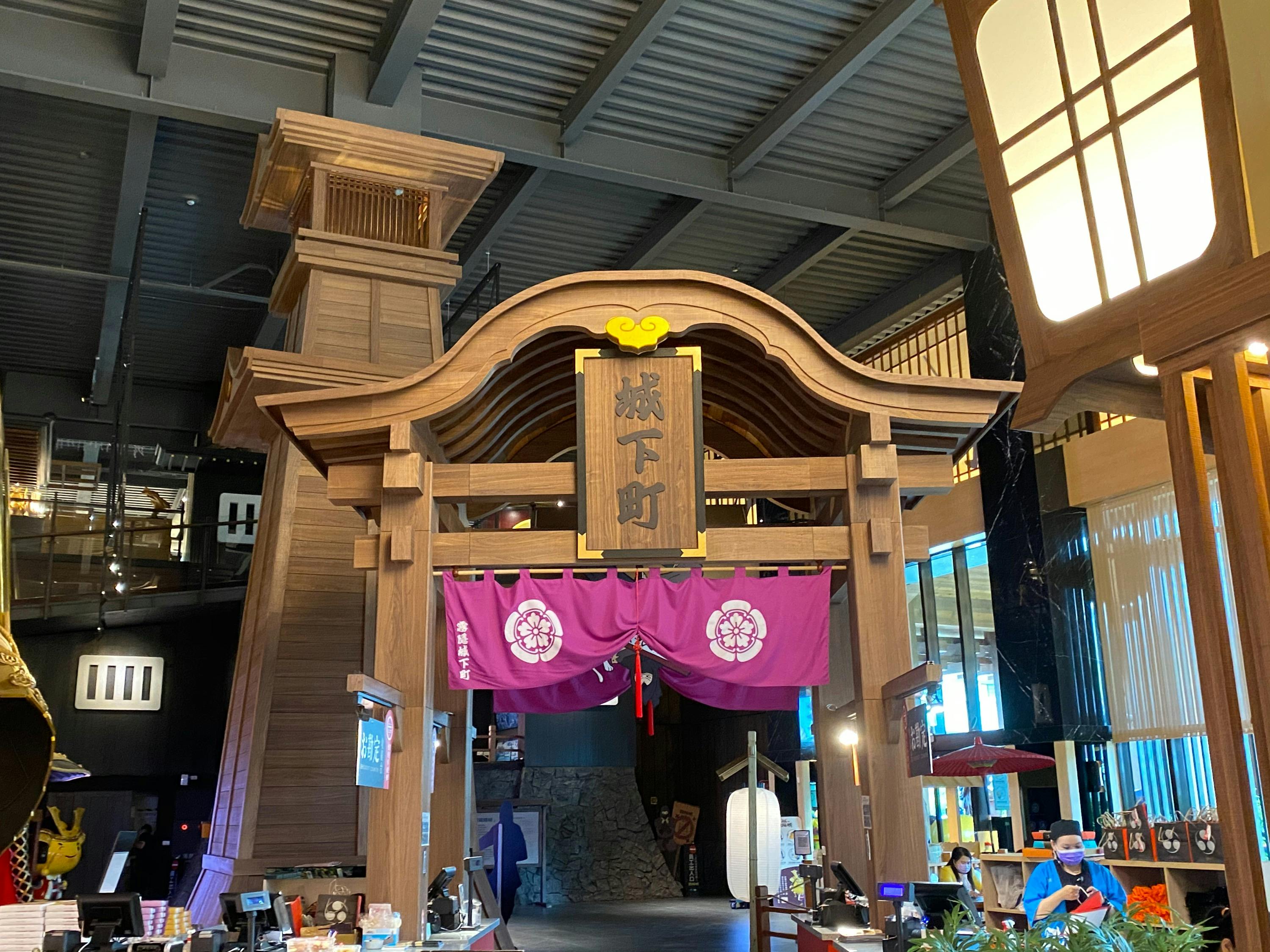 A wooden archway with a sign and purple drapery, situated indoors with a traditional Japanese style design.
