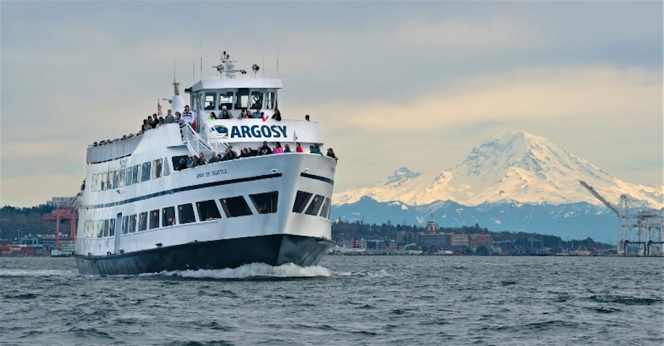 Argosy Cruise boat with Mount Rainier in the background, with people visible on the outer decks.