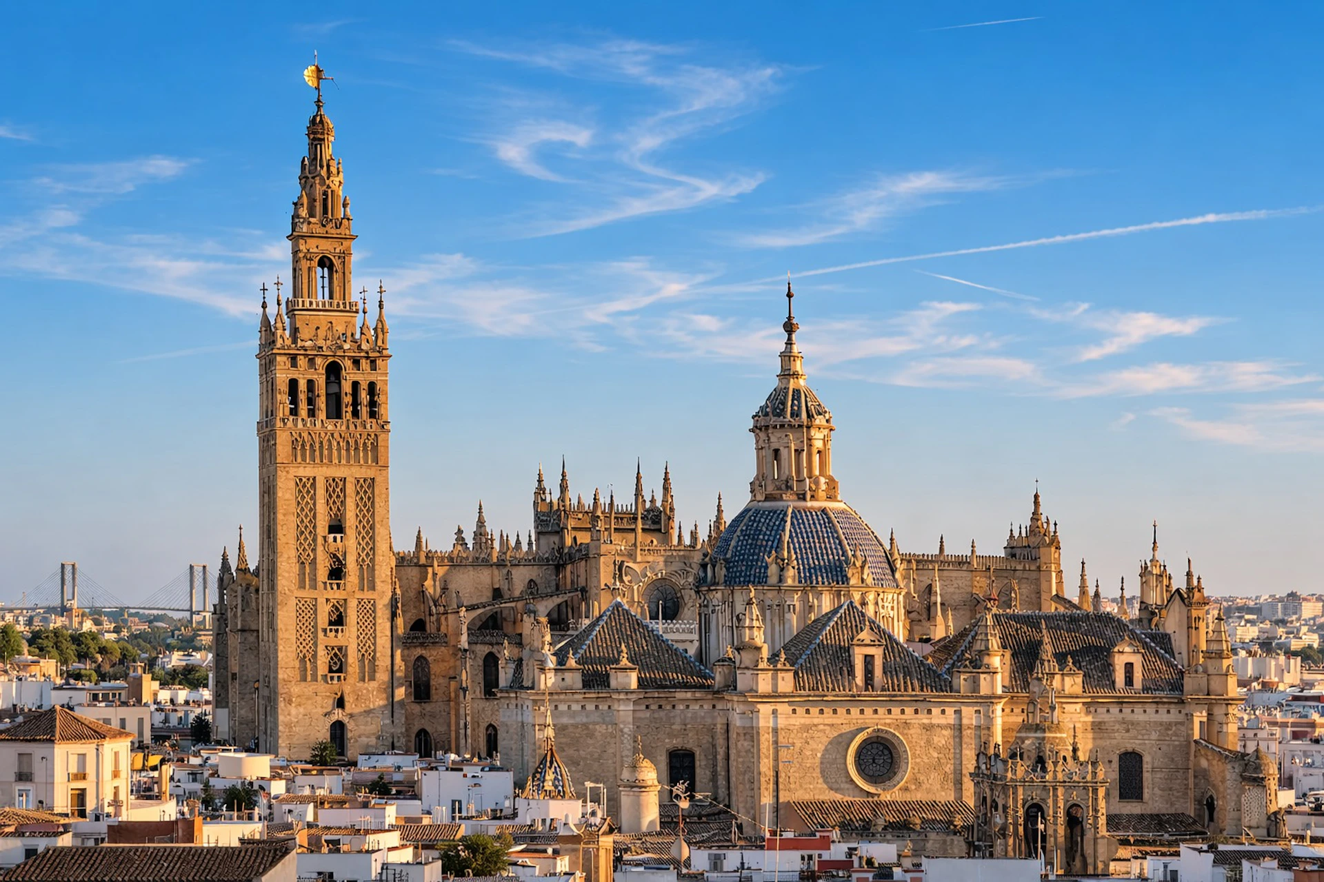 A historic cathedral with intricate architecture, featuring a tall bell tower and ornate domes under a clear blue sky.